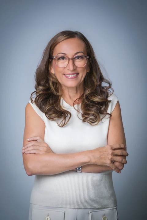 Dr. Isabella Wilden in weißem Oberteil, mit verschränkten Armen, lächelnd